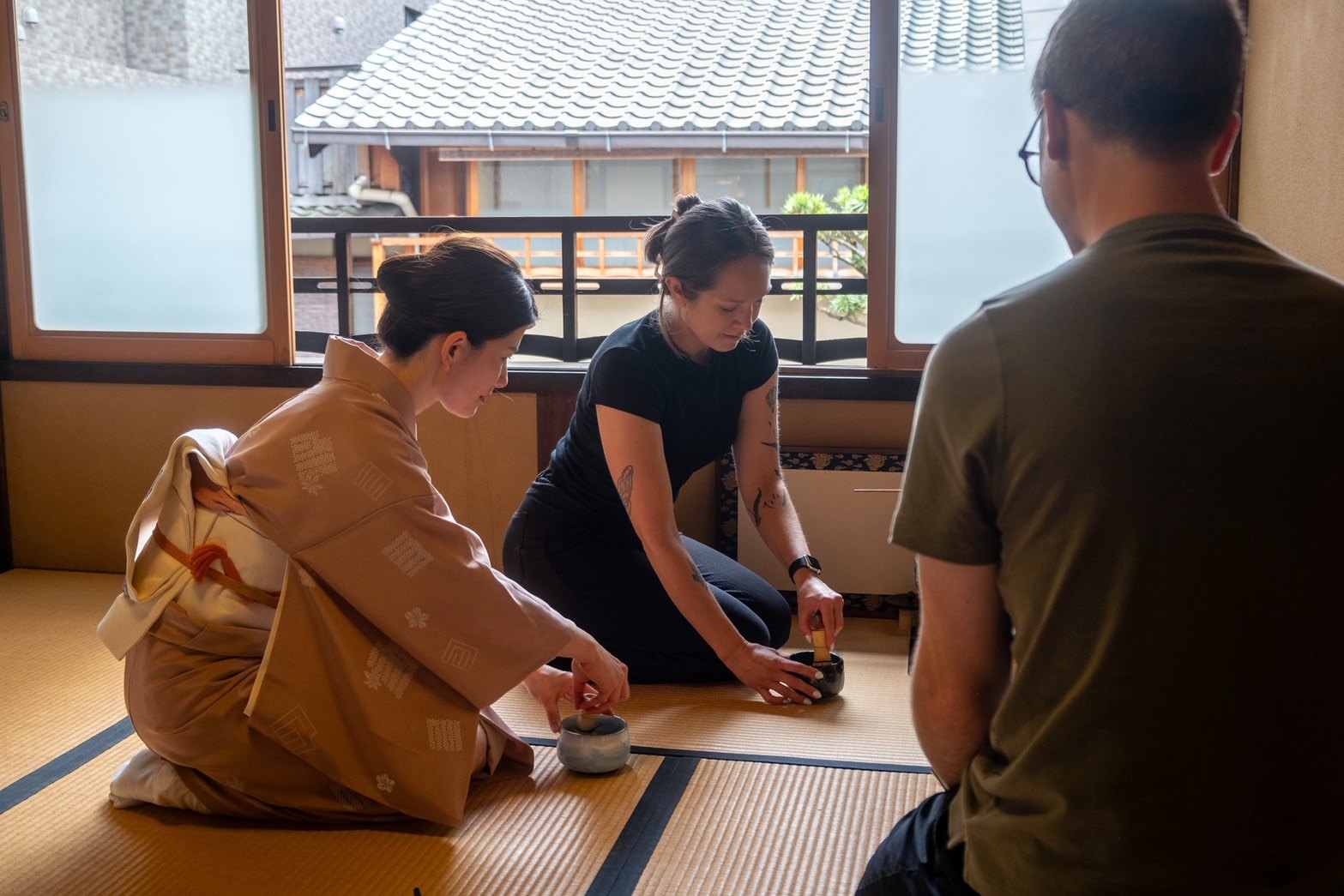 A kimono-clad host guiding visitors through preparing tea