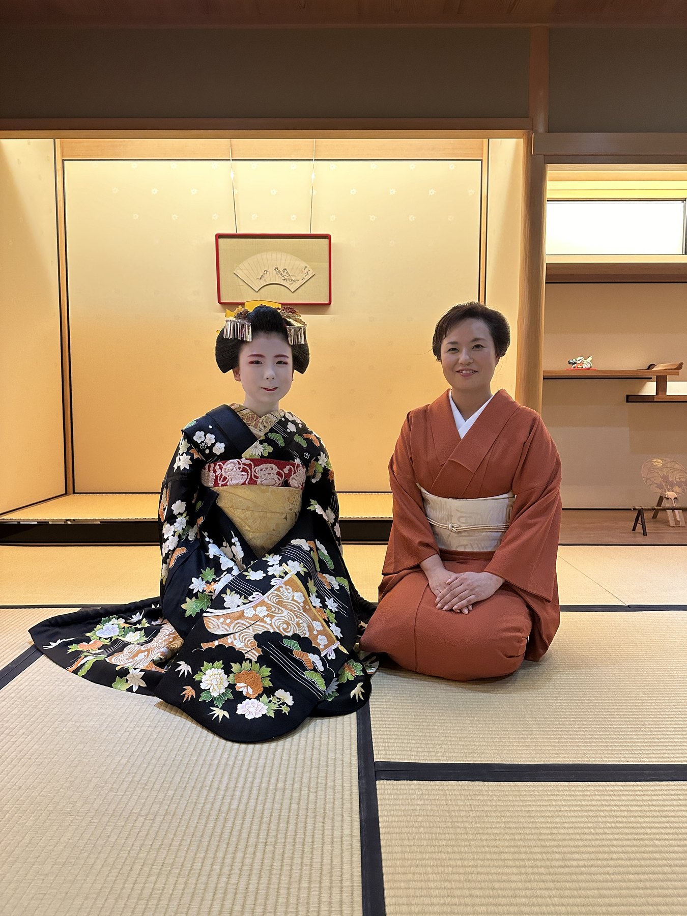 Two women in traditional kimono seated in a Japanese room