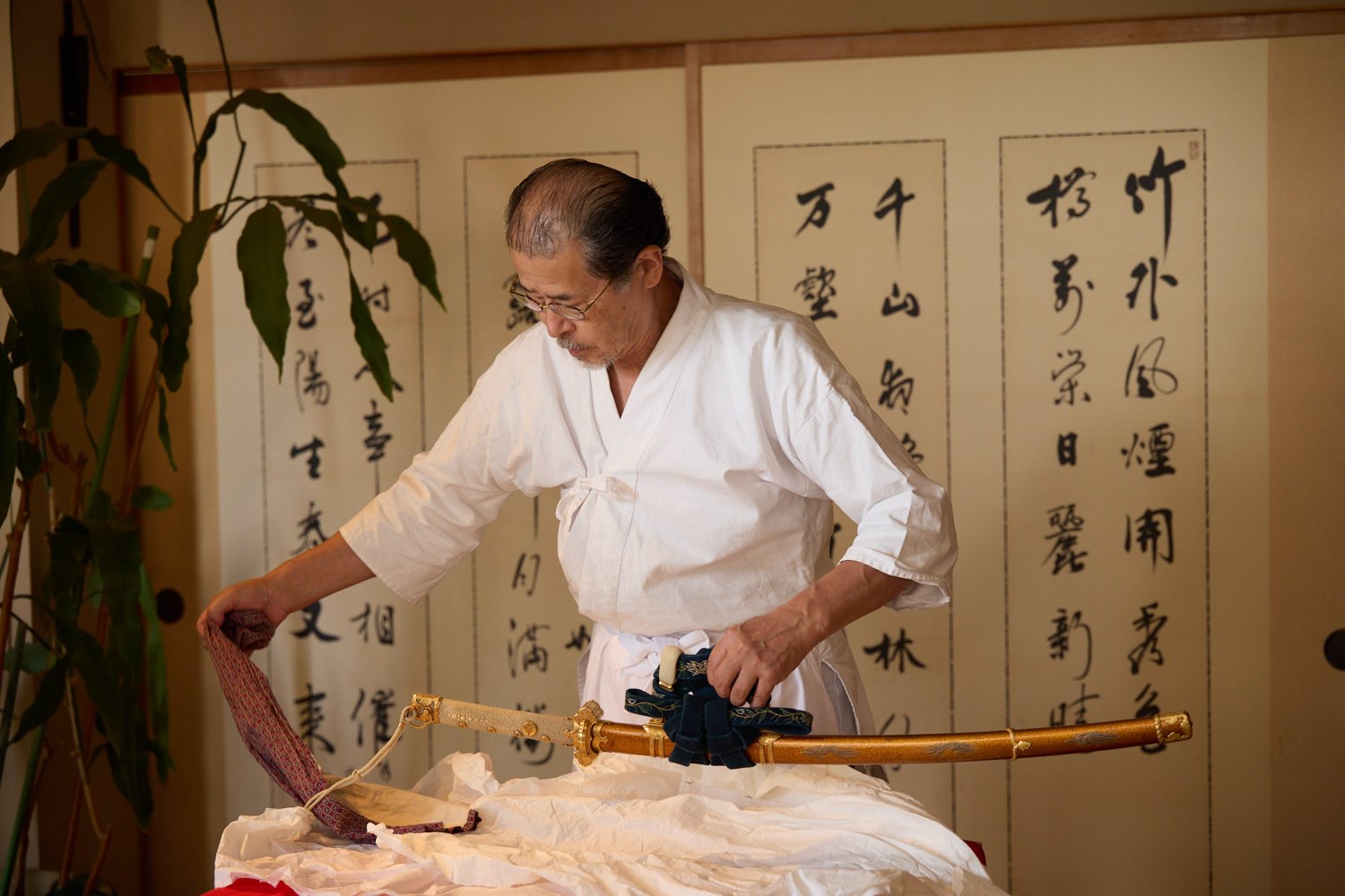 A craftsman displaying a Japanese sword in a traditional room