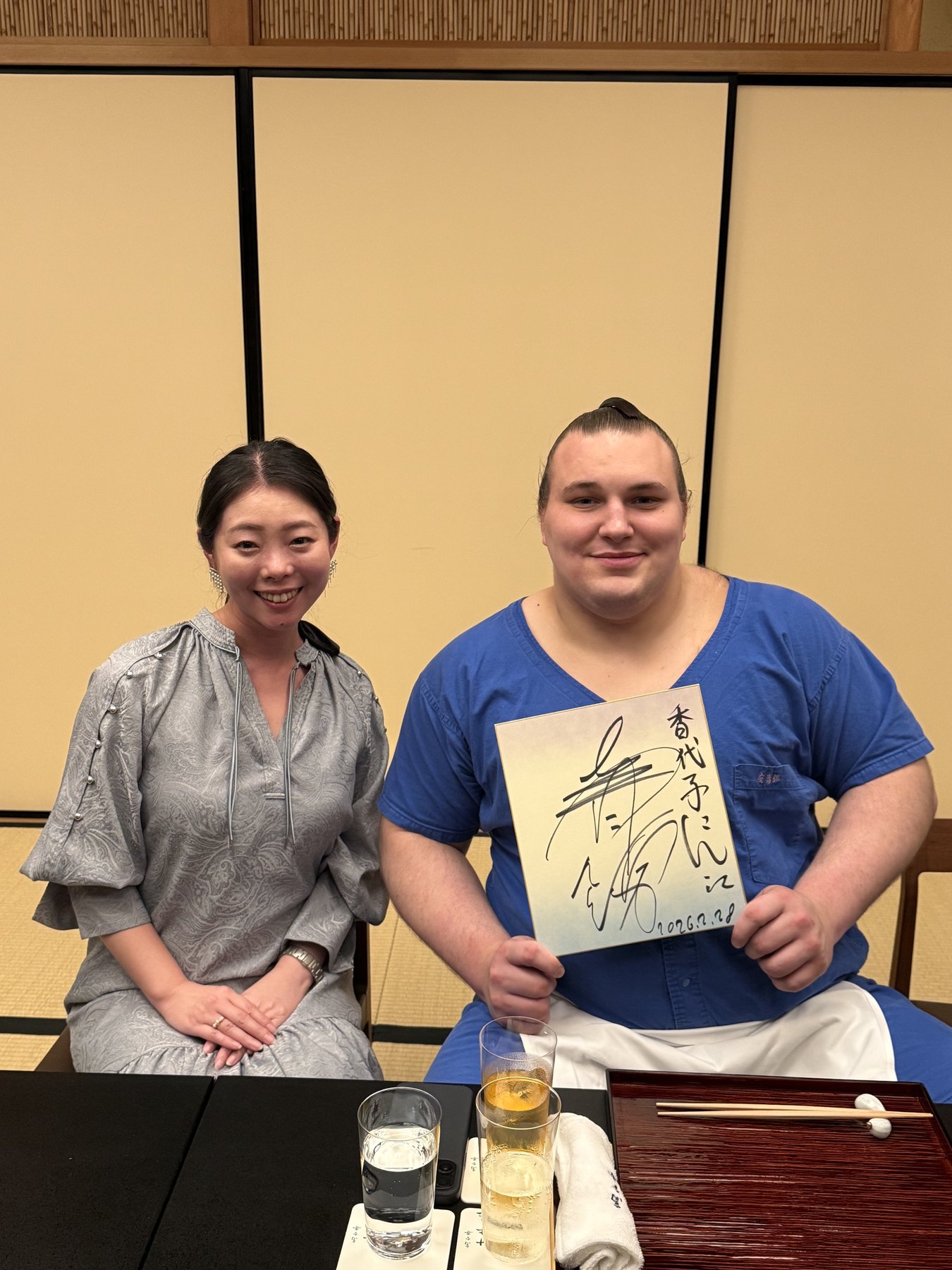 A guest and a sumo wrestler seated together at a dining table